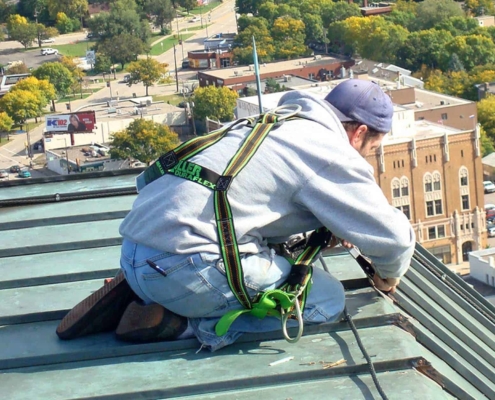Roofer working on top of green metal roof