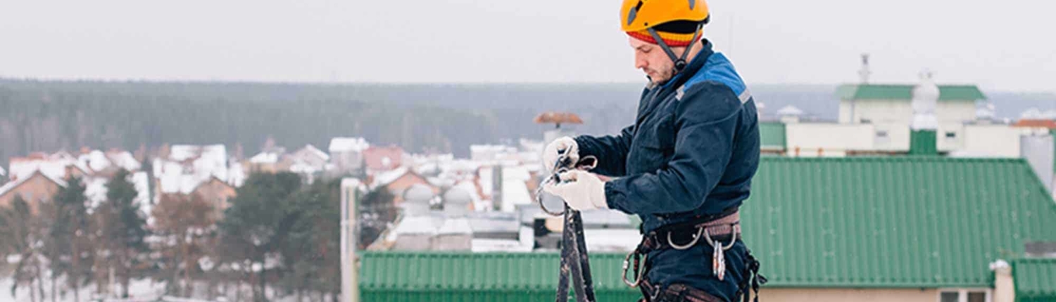 Roofer on top of building with snow