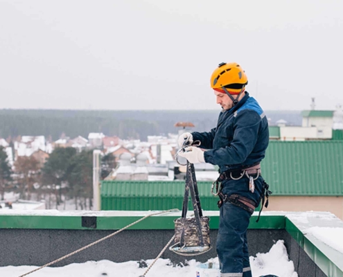 Roofer on top of building with snow