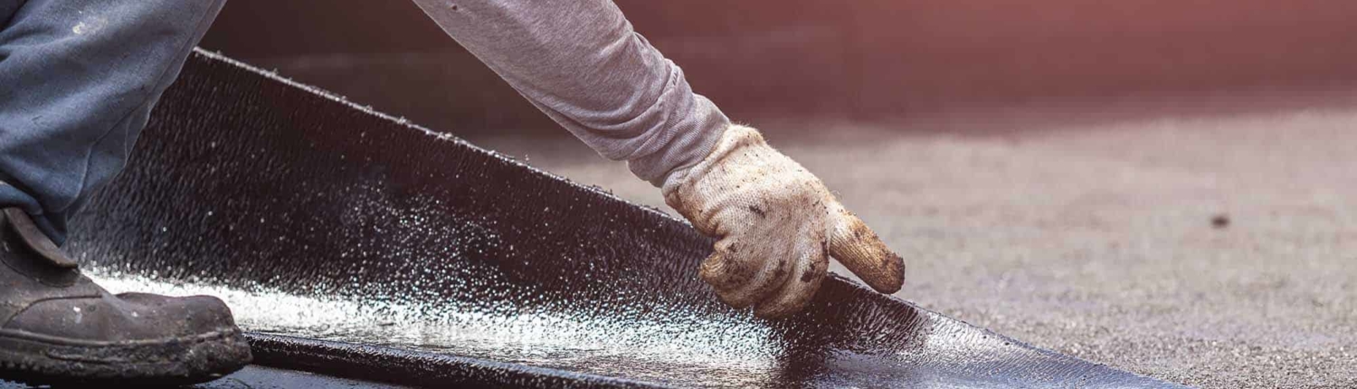 Roofing worker laying asphalt sheet