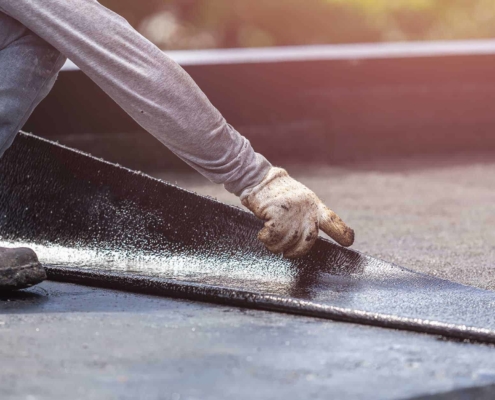 Roofing worker laying asphalt sheet