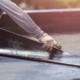 Roofing worker laying asphalt sheet