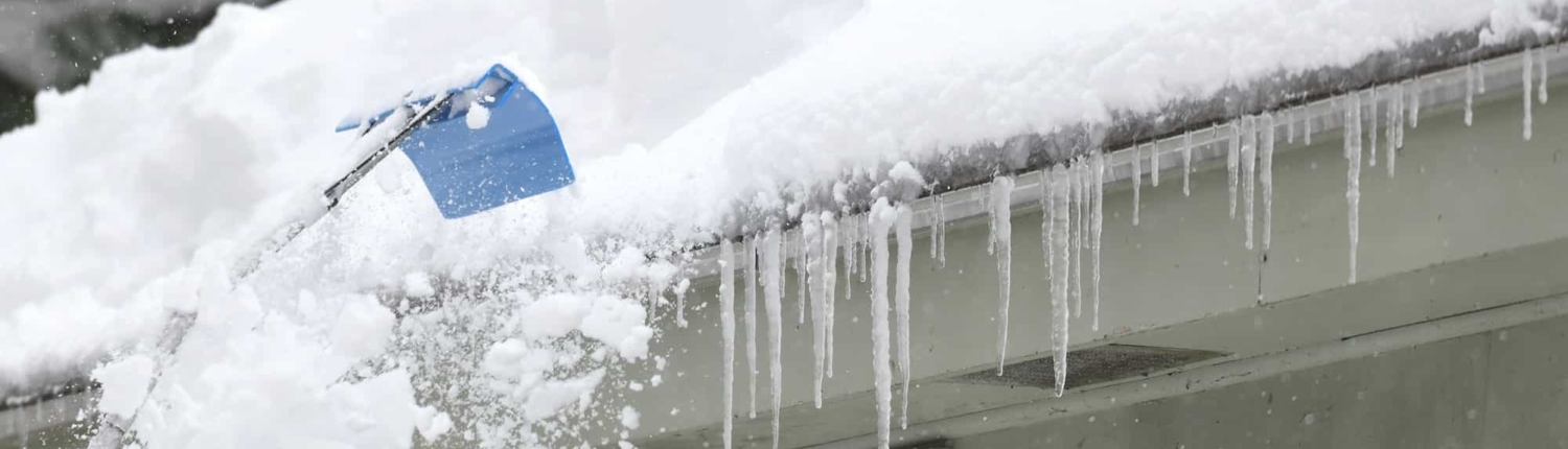 Homeowner. shoving snow off shingled roof