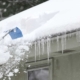 Homeowner. shoving snow off shingled roof