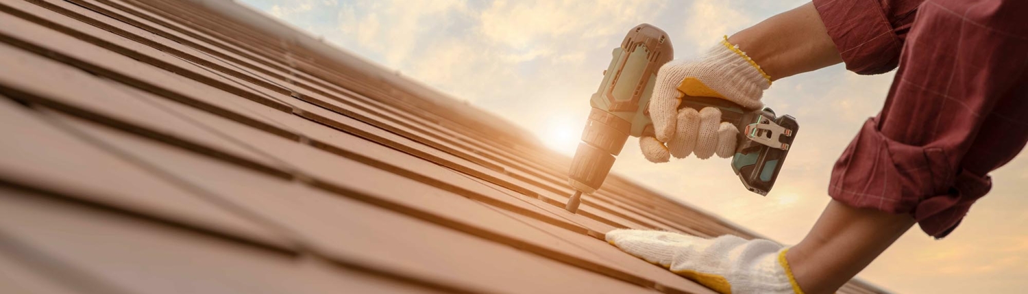 Side view of a repairman installing new roof tiles