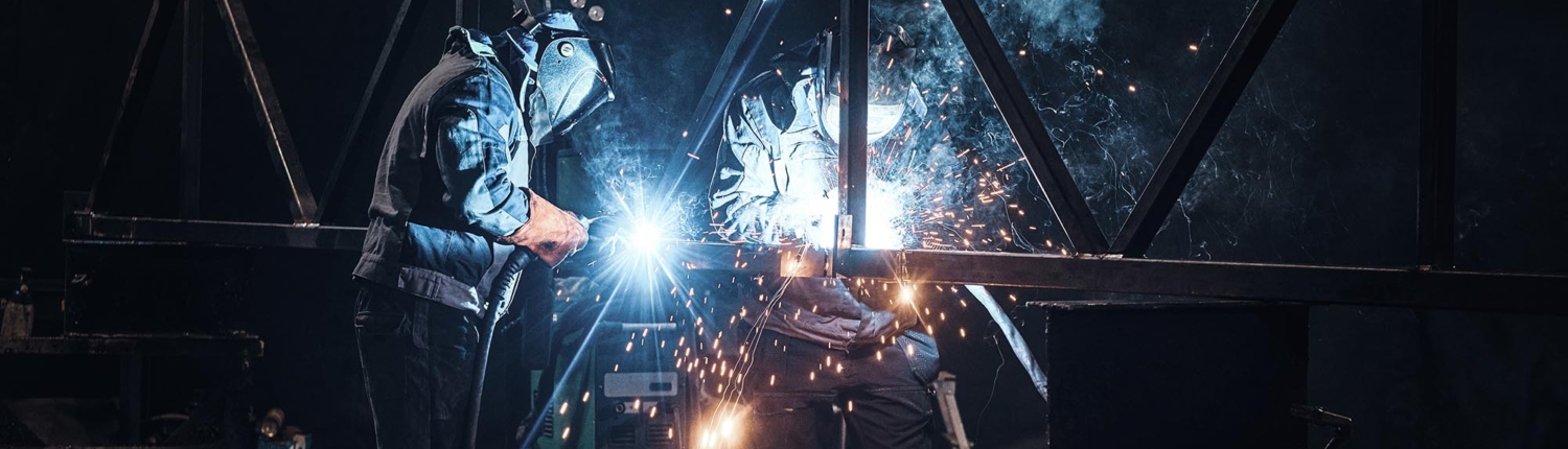 Side view of two workers welding together a structure
