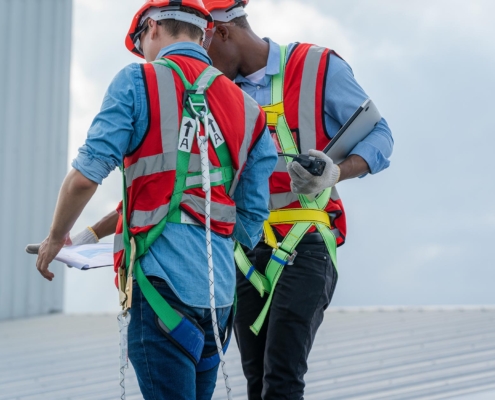 Two professional roofers with clipboard inspecting commercial roof