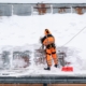 Worker cleaning snow off roof