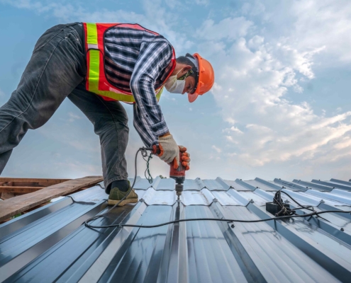 Roof worker installing new metal roof on commercial building
