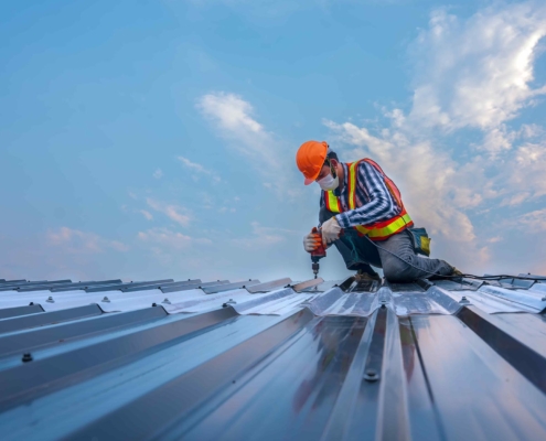Worker installing metal roof on commercial building