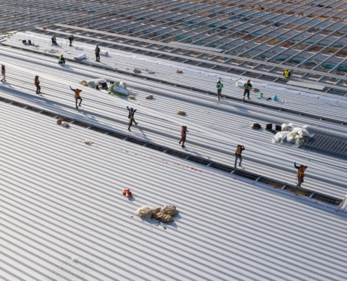 Workers installing metal roof panels on commercial building