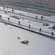 Workers installing metal roof panels on commercial building
