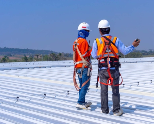 Two workers inspecting metal roof