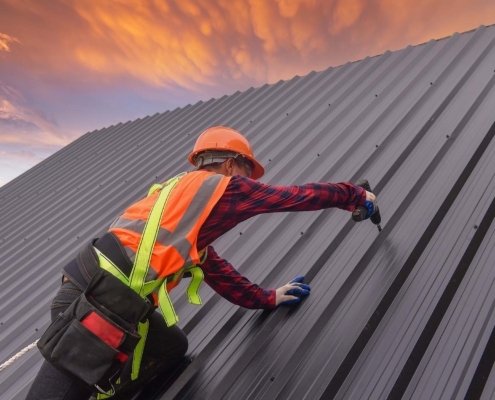 worker drilling into metal roof